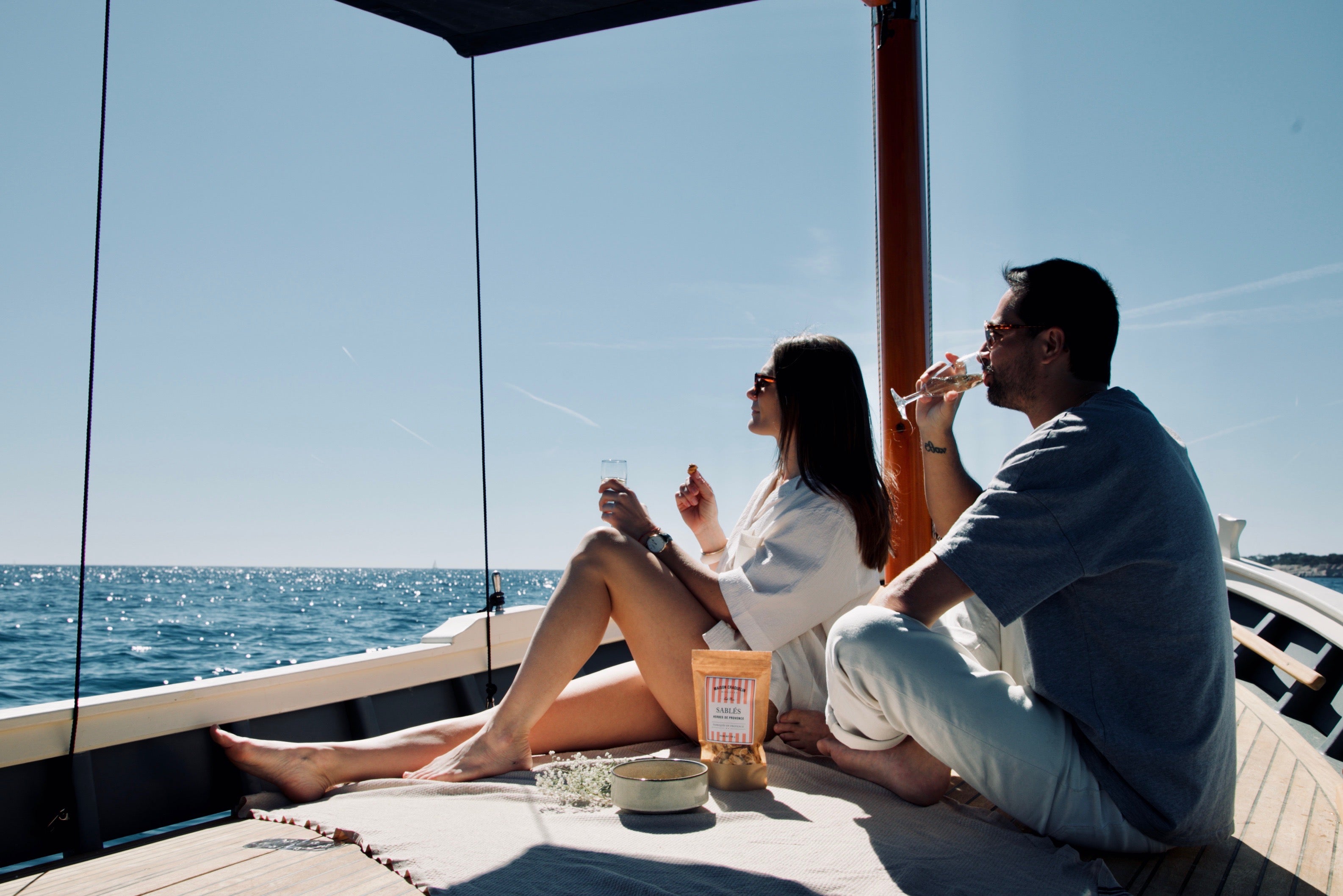 Apéritif sur le pont d'un bateau avec un sachet de sablés aux herbes de Provence Maison Craquelin